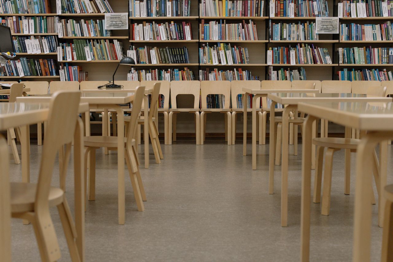 Sleek library interior showcasing rows of books and minimalist wooden furniture.